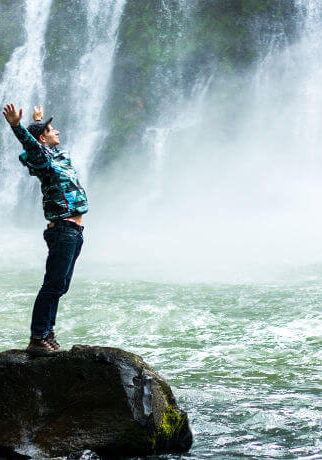 Man on a rock in front of waterfall expereincing the freedom of intuitive, psychic, theta healing with Colby Wilk