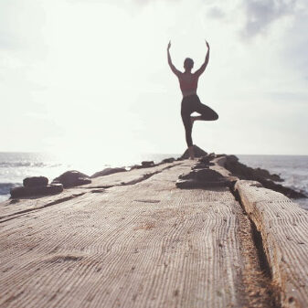 Person doing yoga pose on a dock regaing balance like after a spiritual, intuitive , psychci healing with Colby Wilk